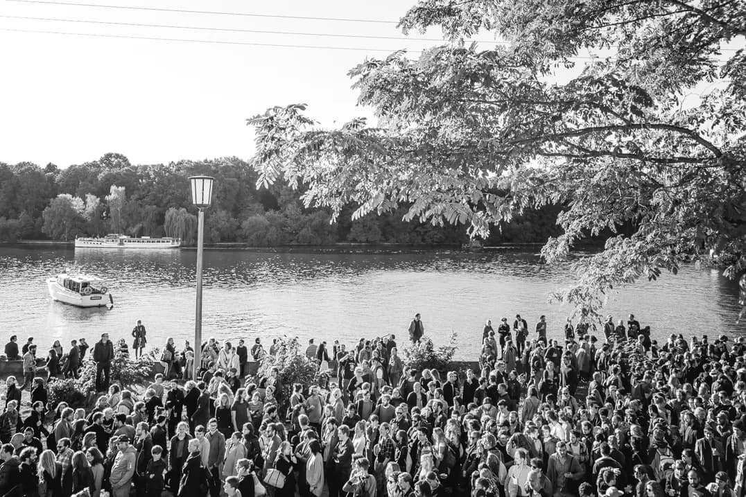 Crowd gathered by the river Spree as boats arrive at Funkhaus